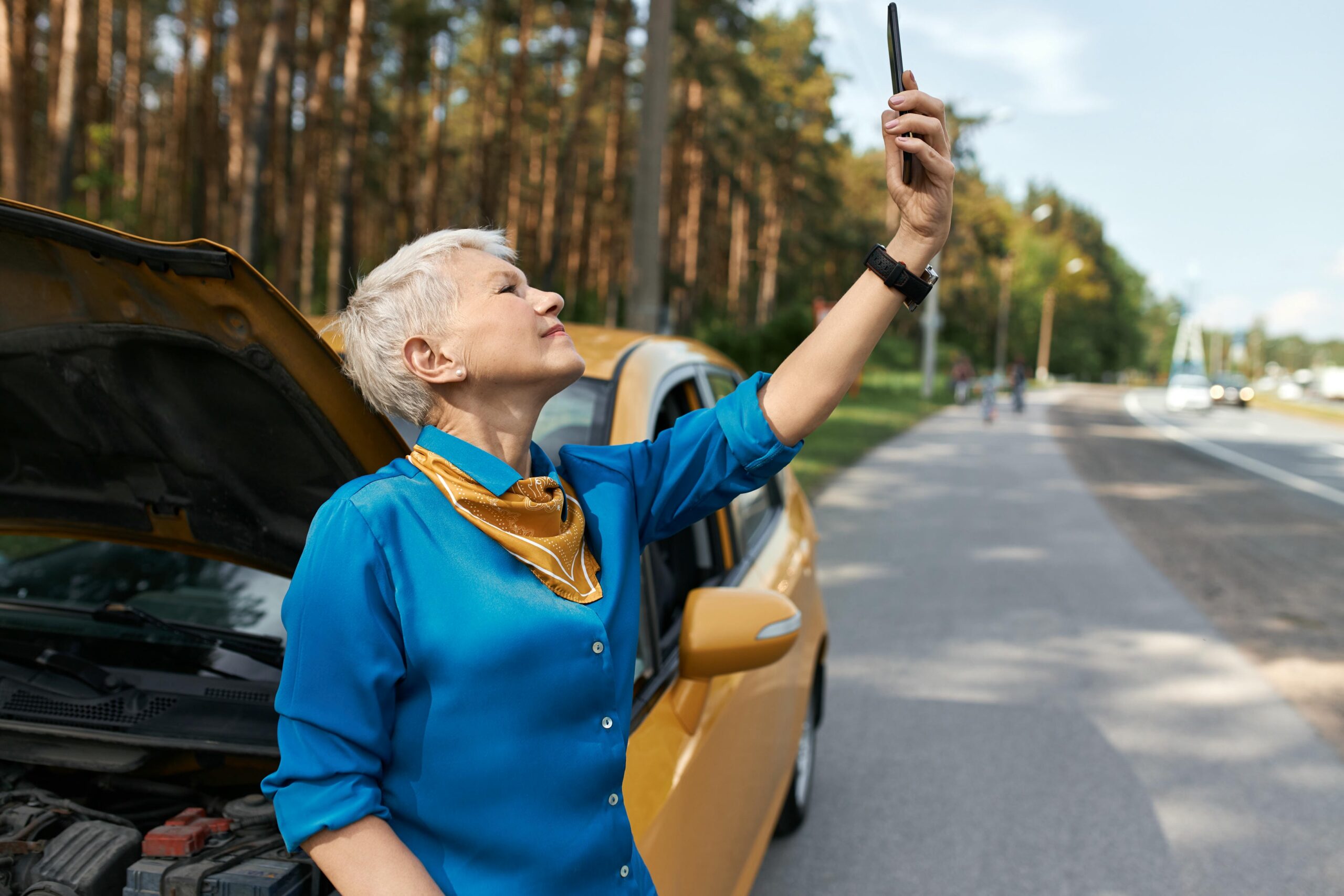 Outdoor Image Unhappy Middle Aged Woman Standing Road By Broken Car With Open Hood Raising Hand With Mobile Phone Looking Network Signal Trying Call Assistance